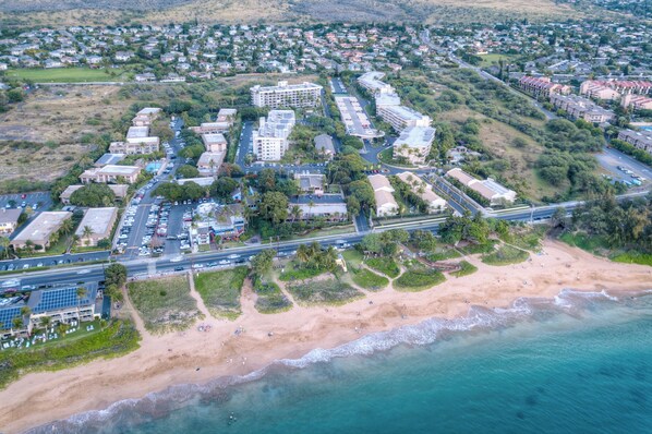 An aerial view of a coastal town with a beachfront, roads, and residential buildings.