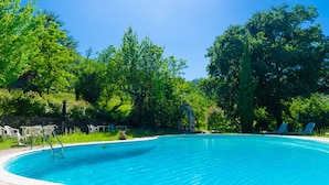 A clear blue swimming pool surrounded by lush greenery and stone walls. - Il Rifugio Pecorella (Alvignano)