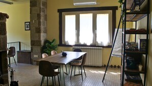 A dining area with a table and chairs, a radiator, and a window with curtains. - Il Rifugio Pecorella (Alvignano)