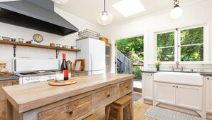A kitchen with a wooden island, white cabinets, and a large window providing a view of greenery.