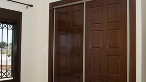 Ein Zimmer mit einer großen Holztür, einem Fenster mit Metallgitter und einer Deckenleuchte.