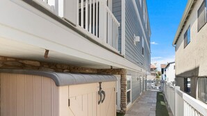 A narrow pathway with a wooden fence on one side and a building on the other.
