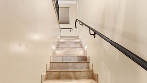 A marble staircase with a black handrail leading to a landing.