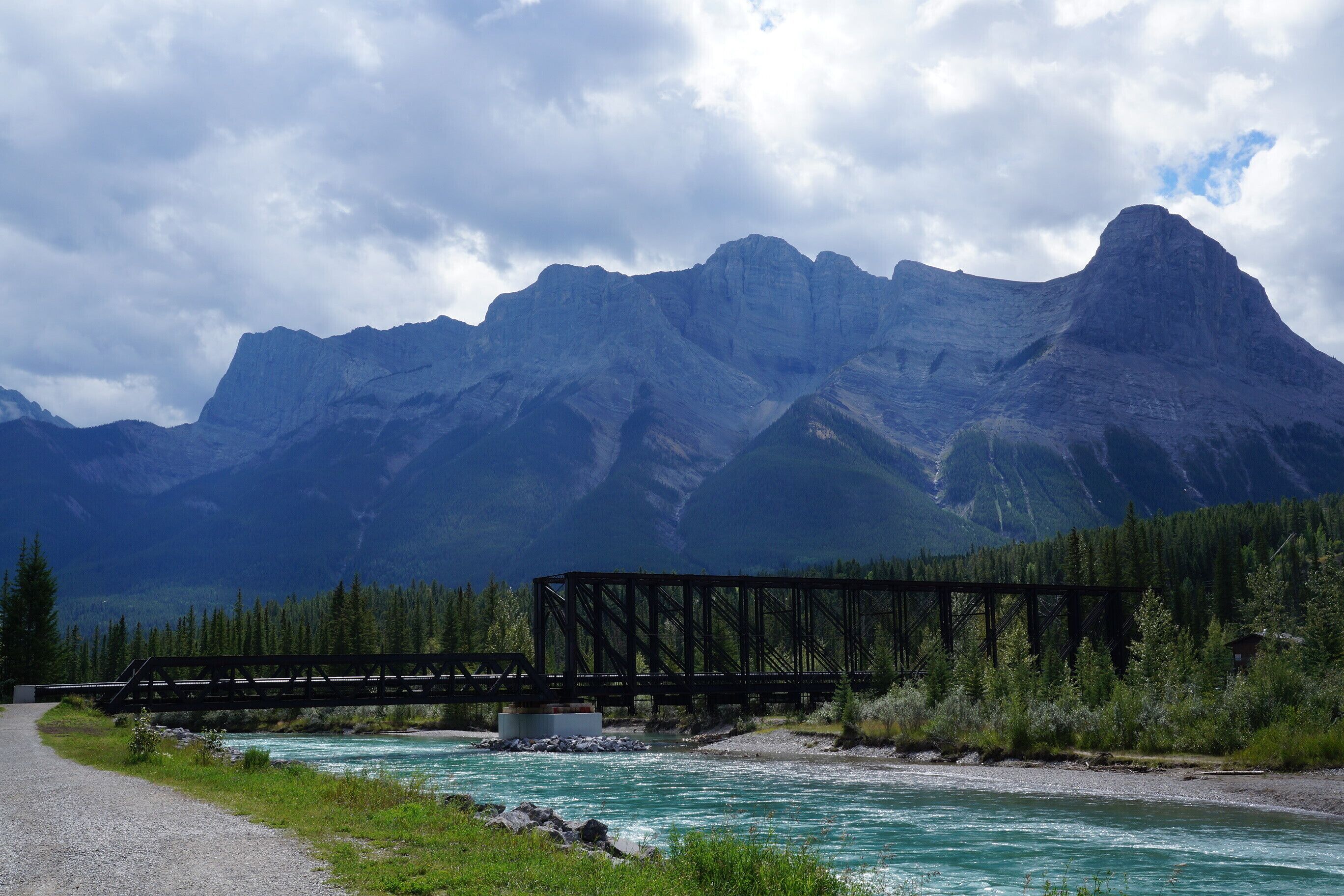 A bridge over a river with mountains in the background.