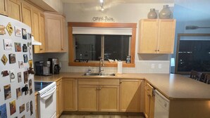 A kitchen with wooden cabinets, a stainless steel sink, and a window above the sink. - Boutique mountain condo with BREATH-TAKING views in the heart of it all! (Canmore)