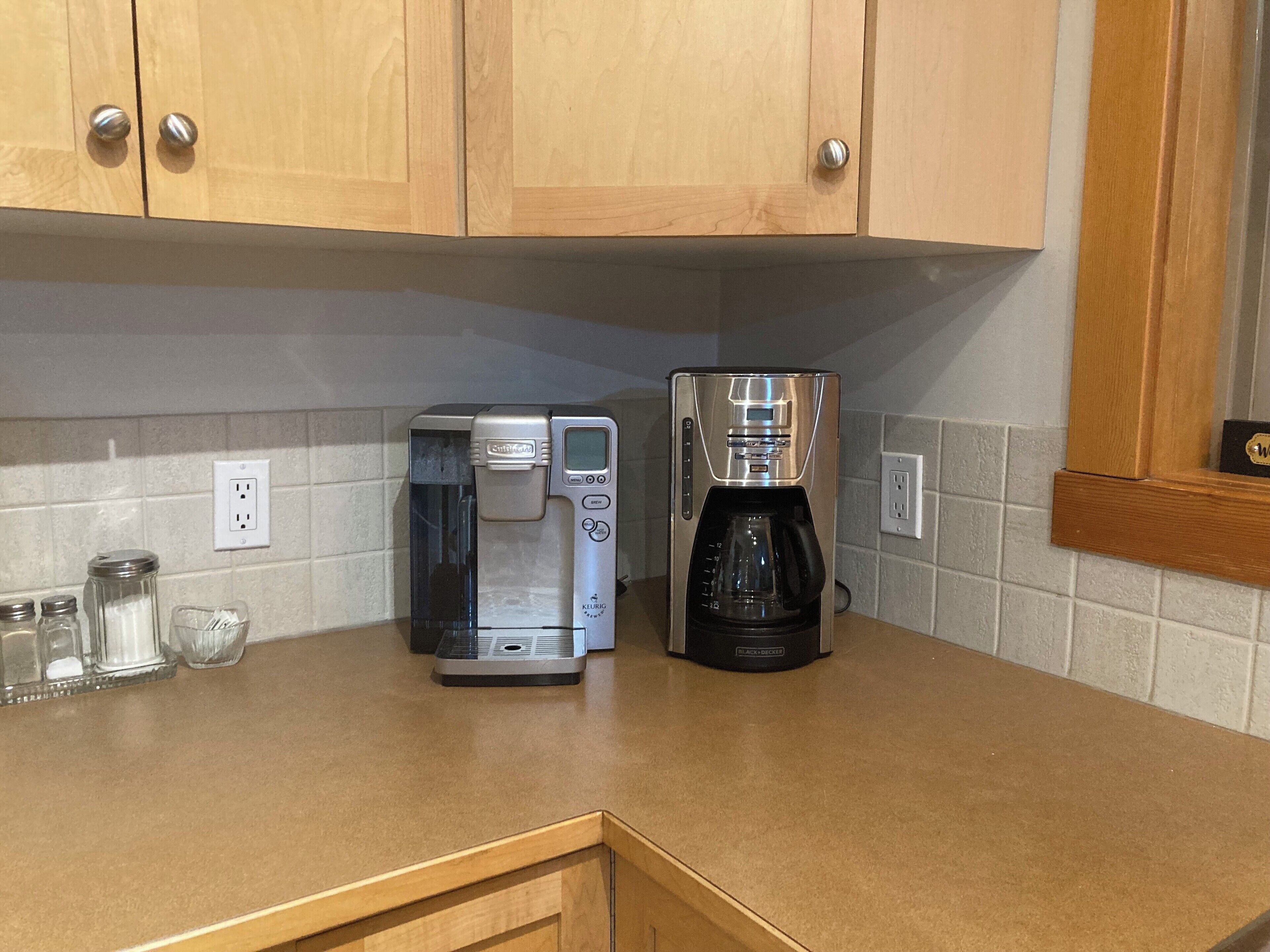 Una cocina con armarios de madera, una cafetera y saleros y pimenteros en la encimera.