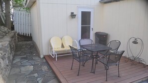 Un patio con un sendero de piedra que lleva a una puerta blanca, una mesa con sillas y un letrero en la pared que dice 'WELCOME'.