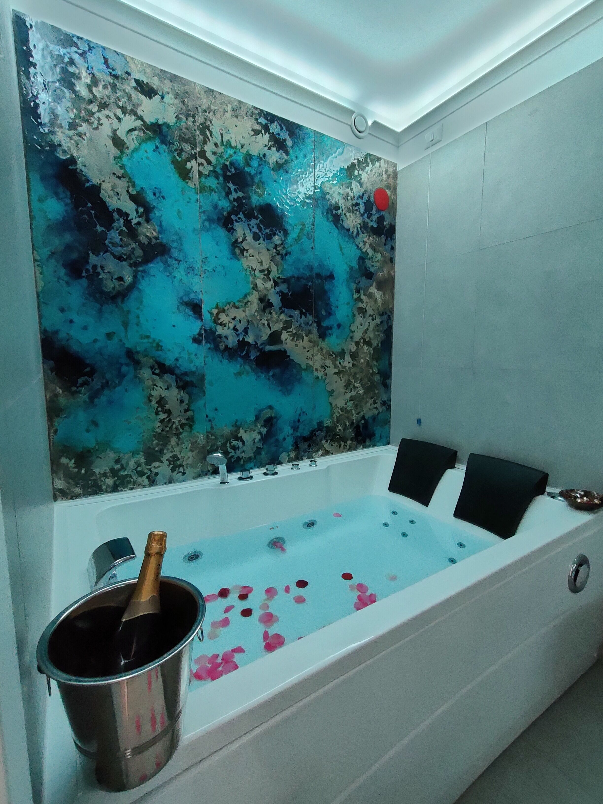A modern bathroom with a large bathtub, a decorative wall, and a champagne bucket.