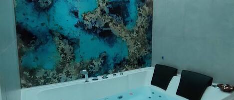 A modern bathroom with a large bathtub, a decorative wall, and a champagne bucket.