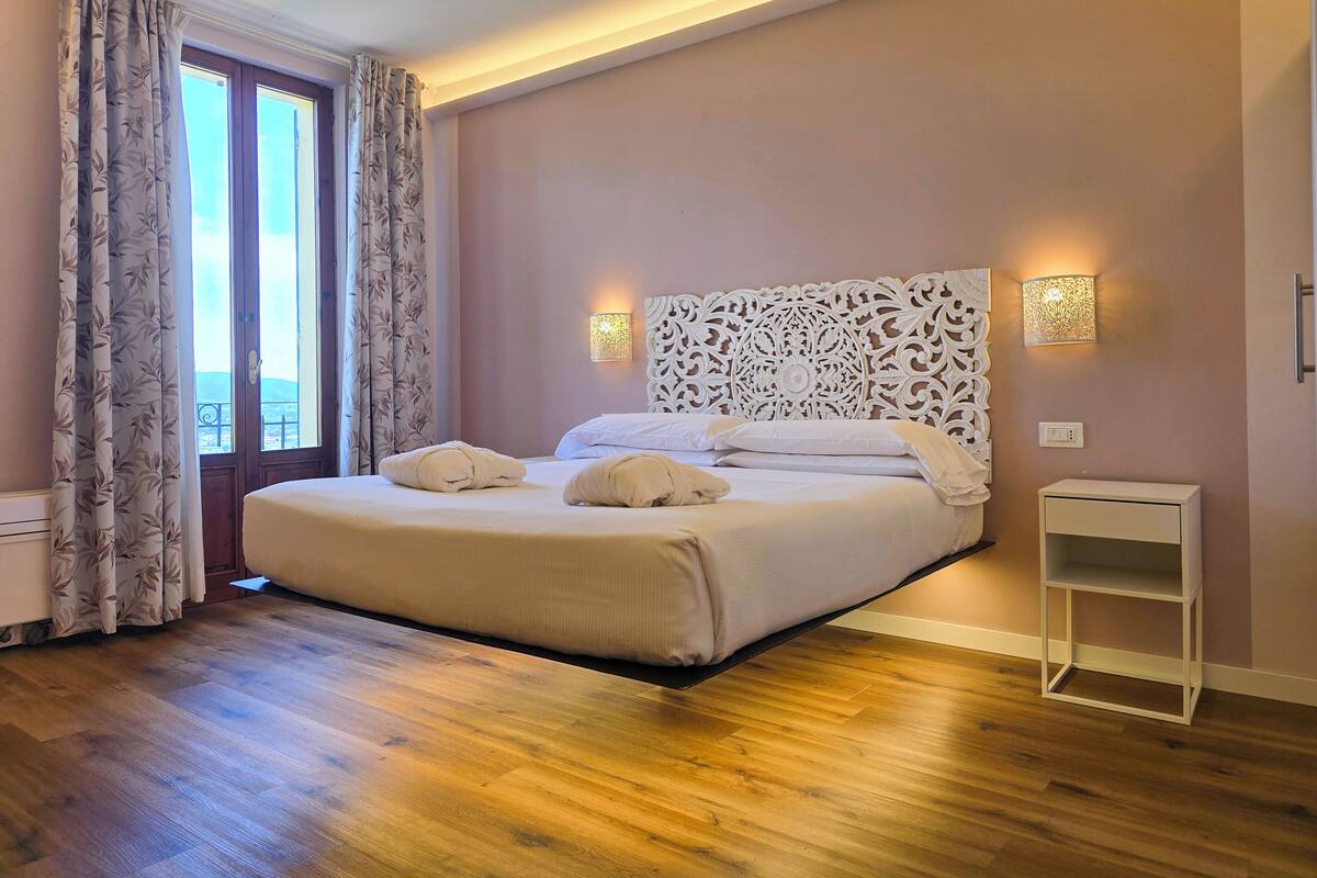 A neatly made bed with two pillows and a bedside table with a lamp.