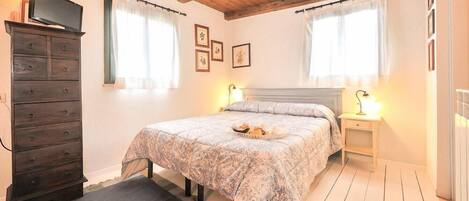 A bedroom with a bed, a dresser, two bedside tables with lamps, and a television on a dresser.