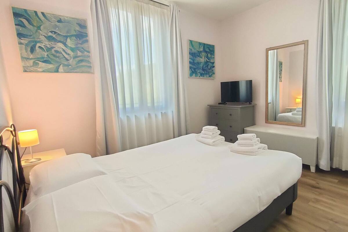 A hotel room with a large bed, a television on a dresser, and artwork on the walls.