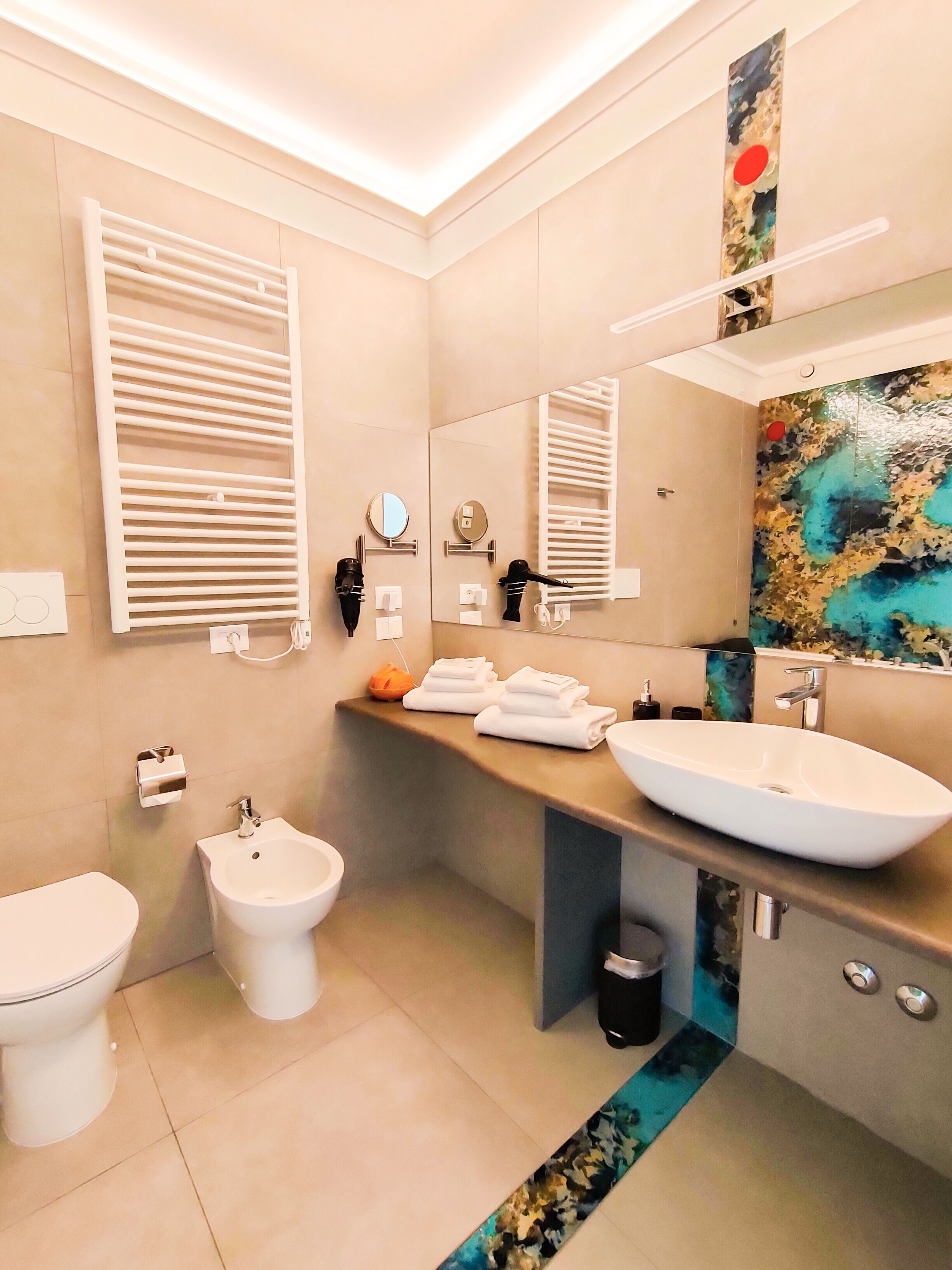 A modern bathroom with a bidet, toilet, and a large sink.
