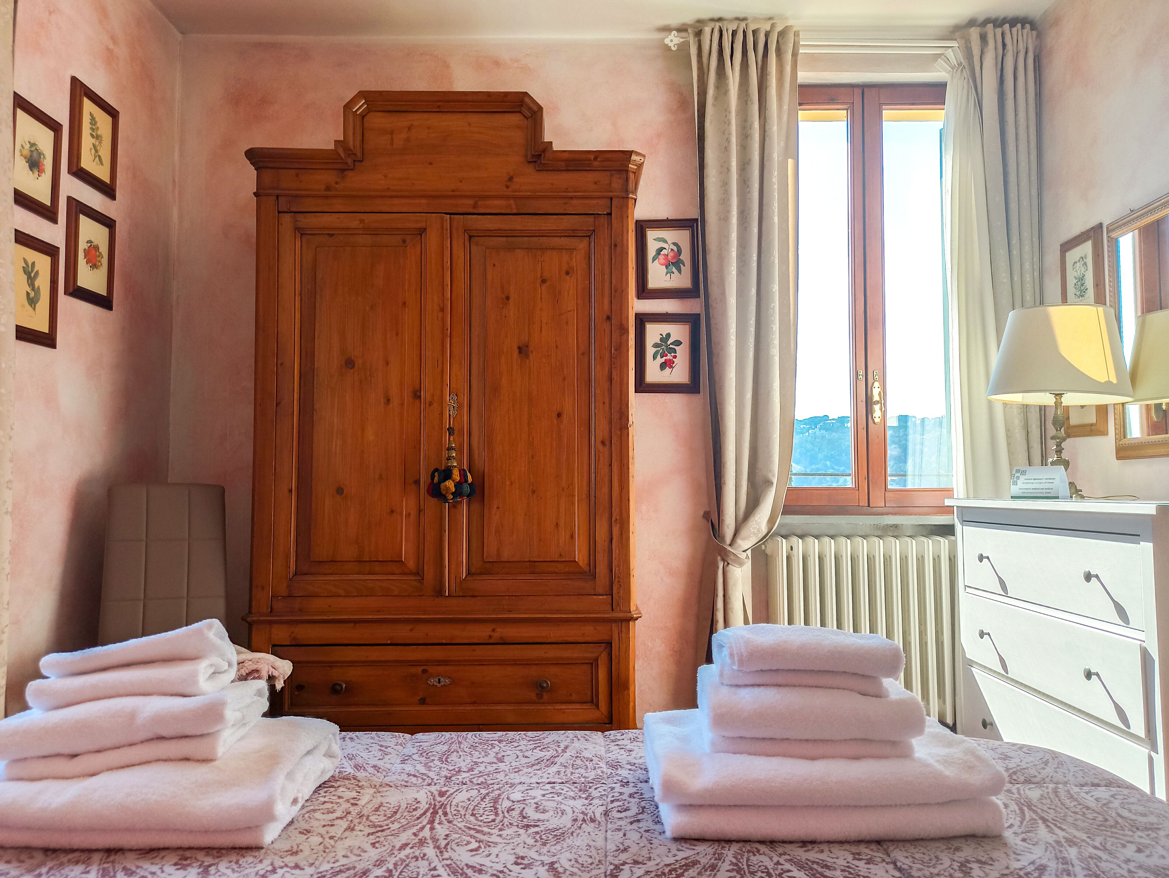 Una habitación con un armario de madera grande, una cama con colcha estampada y una ventana con cortinas.