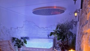 A spa area with a hot tub, wooden loungers, and candles. - Domus Volumnia Country House (Perugia)
