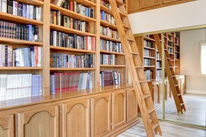 A library with wooden bookshelves and a wooden ladder.