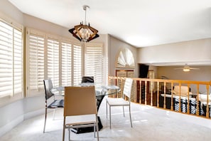 A dining area with a glass table, chairs, and a chandelier.