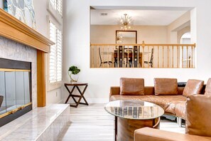 A spacious living room with a marble fireplace, a leather sofa, and a glass coffee table.