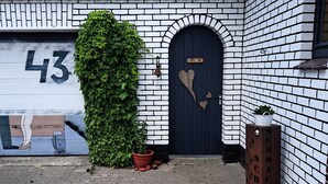 Un edificio con una puerta negra, un portón de garaje con el número 43 y una decoración con forma de corazón en la puerta.