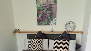 Una cama con ropa de cama gris, cabecero de madera y un reloj de pared.