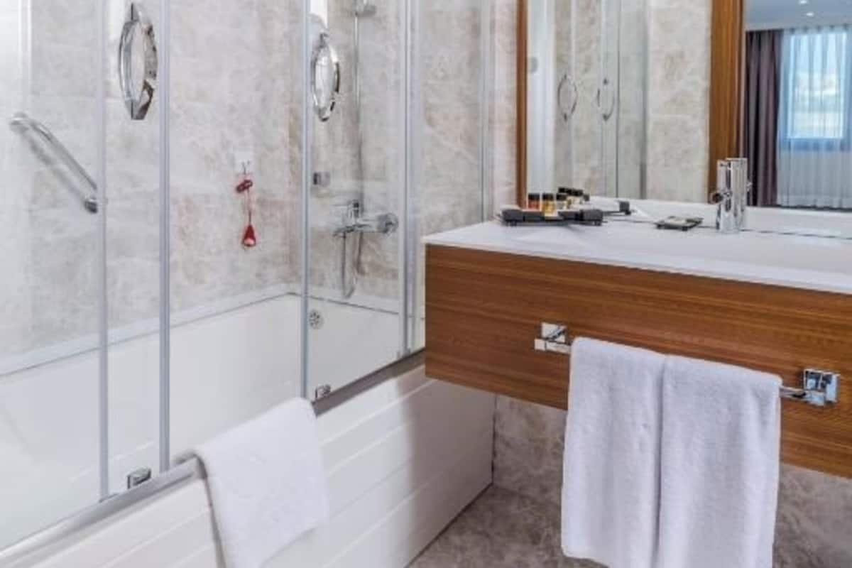 A modern bathroom with a glass-enclosed shower, a wooden vanity, and a large mirror.