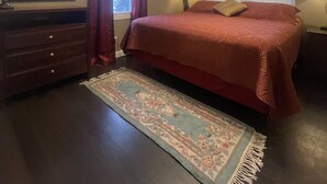 A bedroom with a bed, a dresser, a ceiling fan, and a window with blinds.
