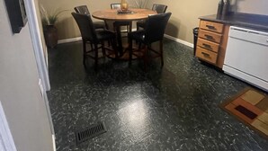 A dining area with a round table, chairs, a ceiling fan, wall-mounted lights, and a decorative vase.