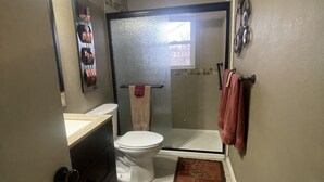 A bathroom with a toilet, shower, and a towel rack.