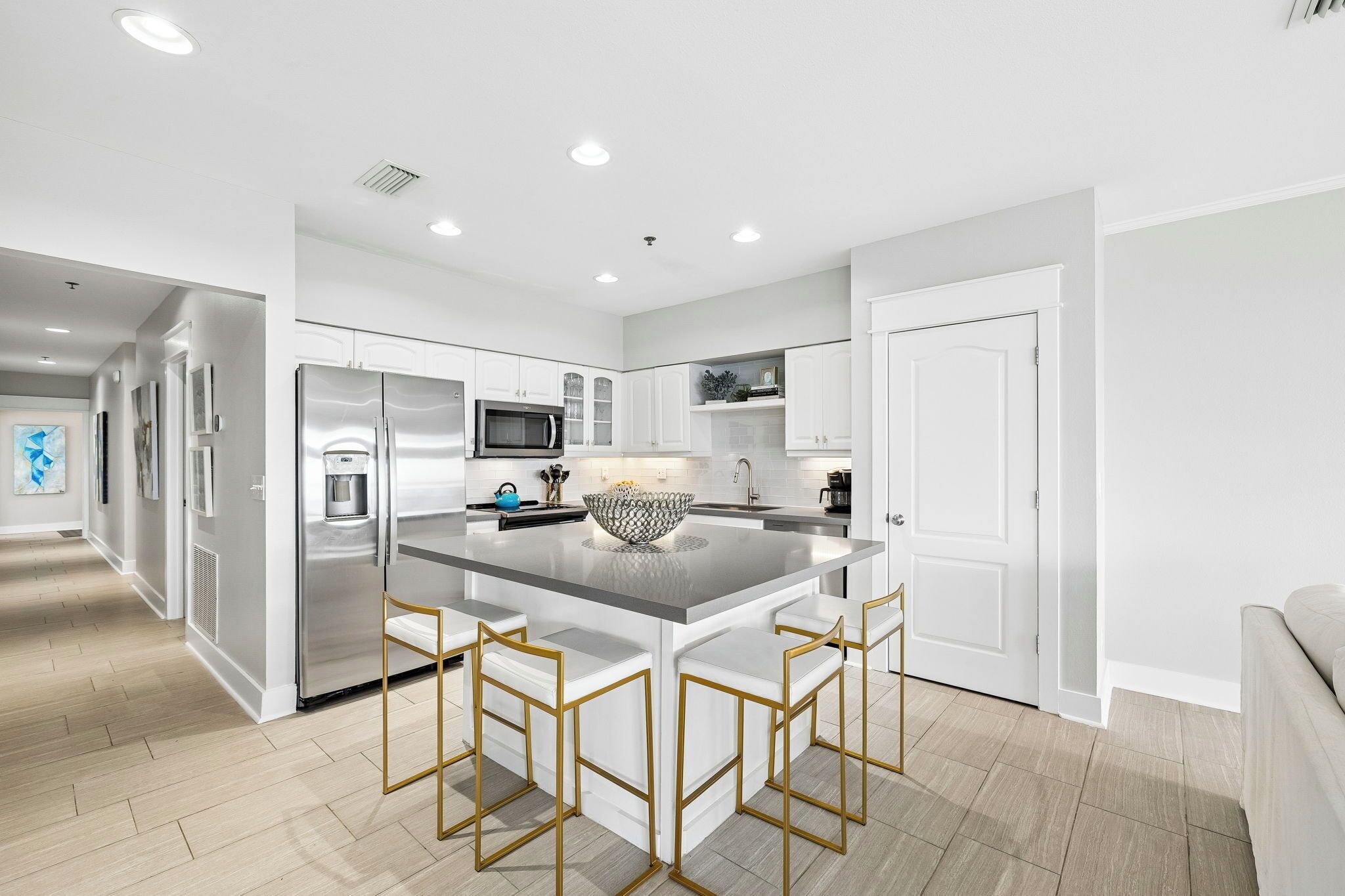 A modern kitchen with a central island, stainless steel appliances, and white cabinetry.