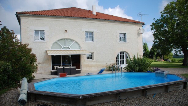A two-story house with a swimming pool, outdoor seating, and a covered patio.