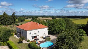 A two-story house with a red-tiled roof, a swimming pool, and a garden.