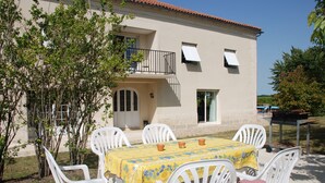 An outdoor dining area with a table set for four, surrounded by white chairs with red and white checkered cushions. - Large luxury Villa located in beautiful countryside close to shops (Saint Ciers du Taillon)