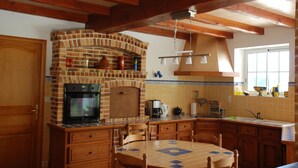 A kitchen with a brick oven, wooden cabinets, a tiled backsplash, and a window with a view. - Large luxury Villa located in beautiful countryside close to shops (Saint Ciers du Taillon)