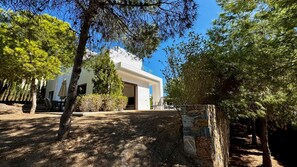 A modern building with a stone wall entrance, a covered outdoor seating area, and a clear sky.