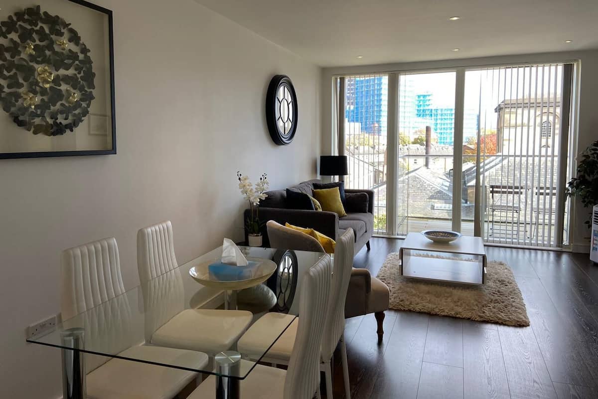 Una sala de estar moderna con una mesa de comedor de cristal, un sofá y un ventanal con vistas a la ciudad.