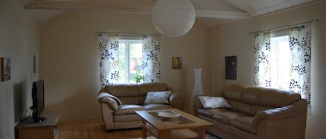 A living room with two sofas, a wooden coffee table, and a television on a stand.