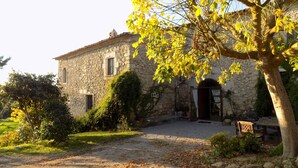 A stone building with a gravel driveway, a wooden door, and a small window.