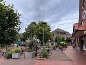 A paved courtyard with outdoor seating, a lamp post, and a variety of potted plants. - Idyllically situated. 90m2 apartment for families + travelers up to 5 persons + garden + terrace near the North Sea 🐟 (Marienhafen)