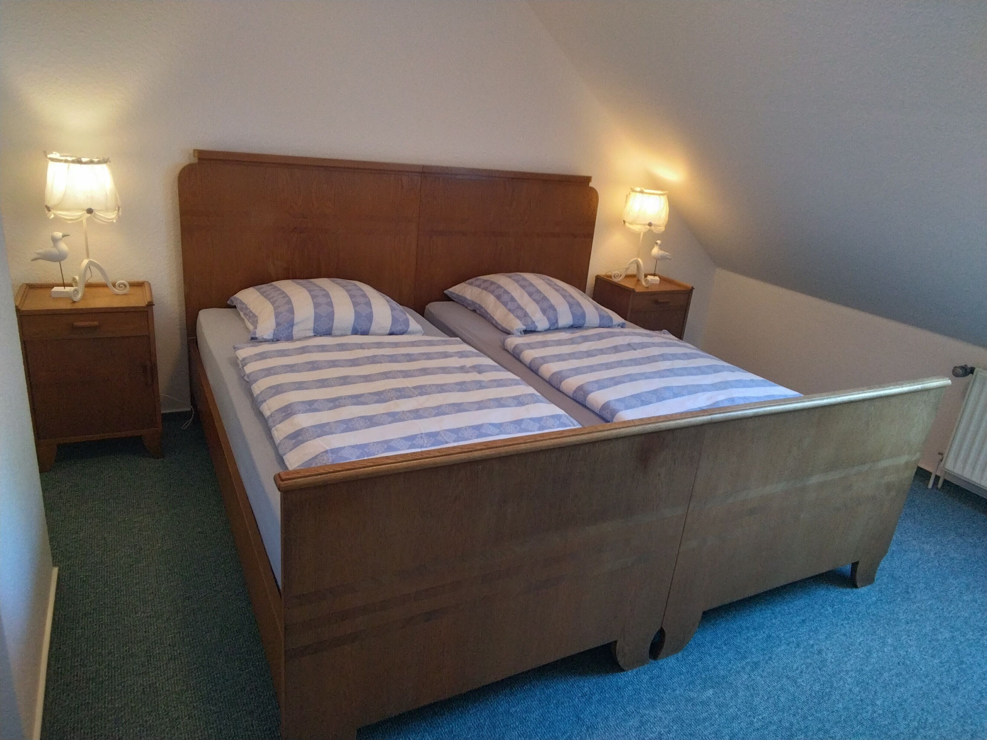 A double bed with striped bedding, two bedside tables with lamps, and a wooden headboard.