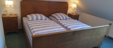 A double bed with striped bedding, two bedside tables with lamps, and a wooden headboard.
