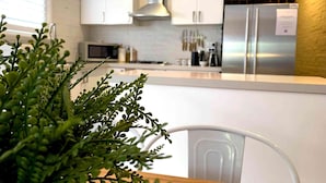 Cozinha moderna com armários brancos, eletrodomésticos de aço inoxidável e uma planta à vista.