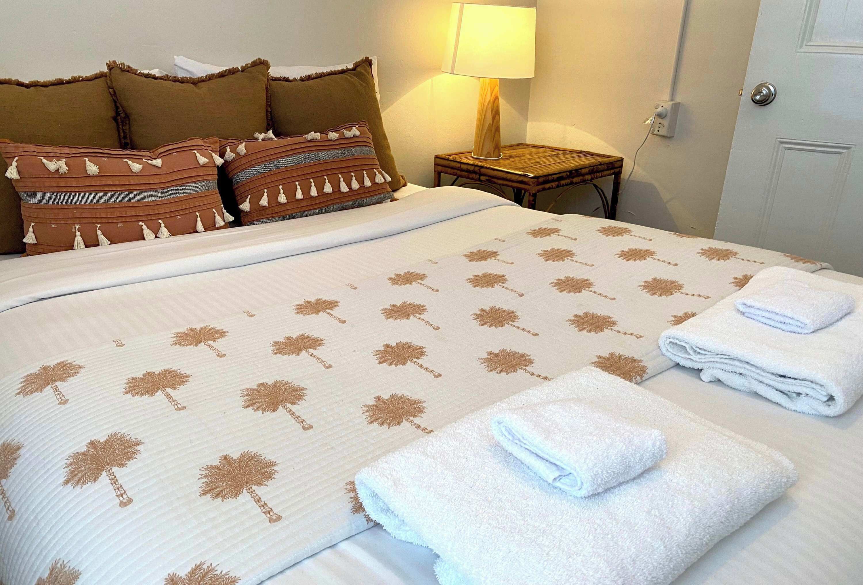 Un lit bien fait, avec une couvre-lit à motifs, des oreillers et des serviettes pliées.
