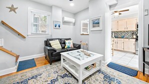 A modern living room with a black leather sofa, a white coffee table, and a ceiling fan. - *3rd to Beach*Beautiful*Clean*Victorian, *Across VETERANS Prk*Beach Haven  (beach haven)