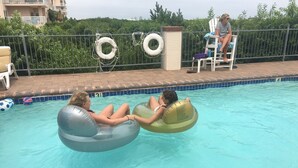 Two people floating in a pool using inflatable rings.