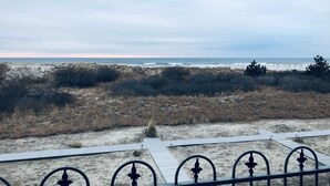A beach view with a sandy path and a metal railing.