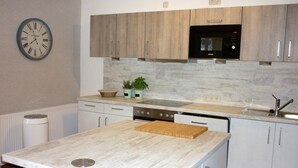 A modern kitchen with white cabinets, a wooden countertop, a microwave, and a clock on the wall. - Holiday house in the green north of the Ruhr area (Dinslaken)