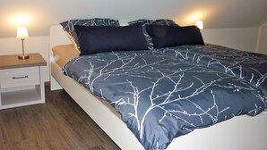 A bedroom with a bed, two bedside tables, and a nightstand. - Holiday house in the green north of the Ruhr area (Dinslaken)