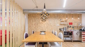 A modern kitchen with a wooden table, white chairs, and a hanging light fixture. - Tomate Rooms (Alicante)