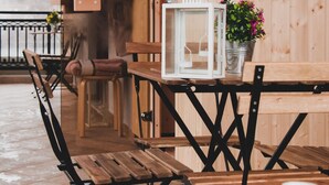 Een houten interieur met een tafel, stoelen, een plant in pot en een digitale thermometer aan de muur.