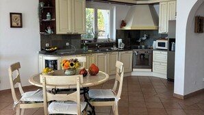 A kitchen with a dining area, featuring a round table with chairs, a stove, and cabinets. - Enjoy Your Front Row Villa On The Adriatic Sea (Pisak)
